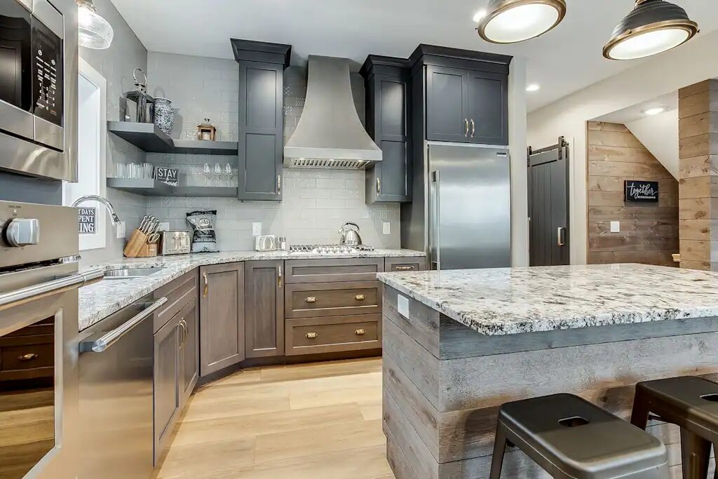 The kitchen with dark cabinetry, a granite island and professional appliances.